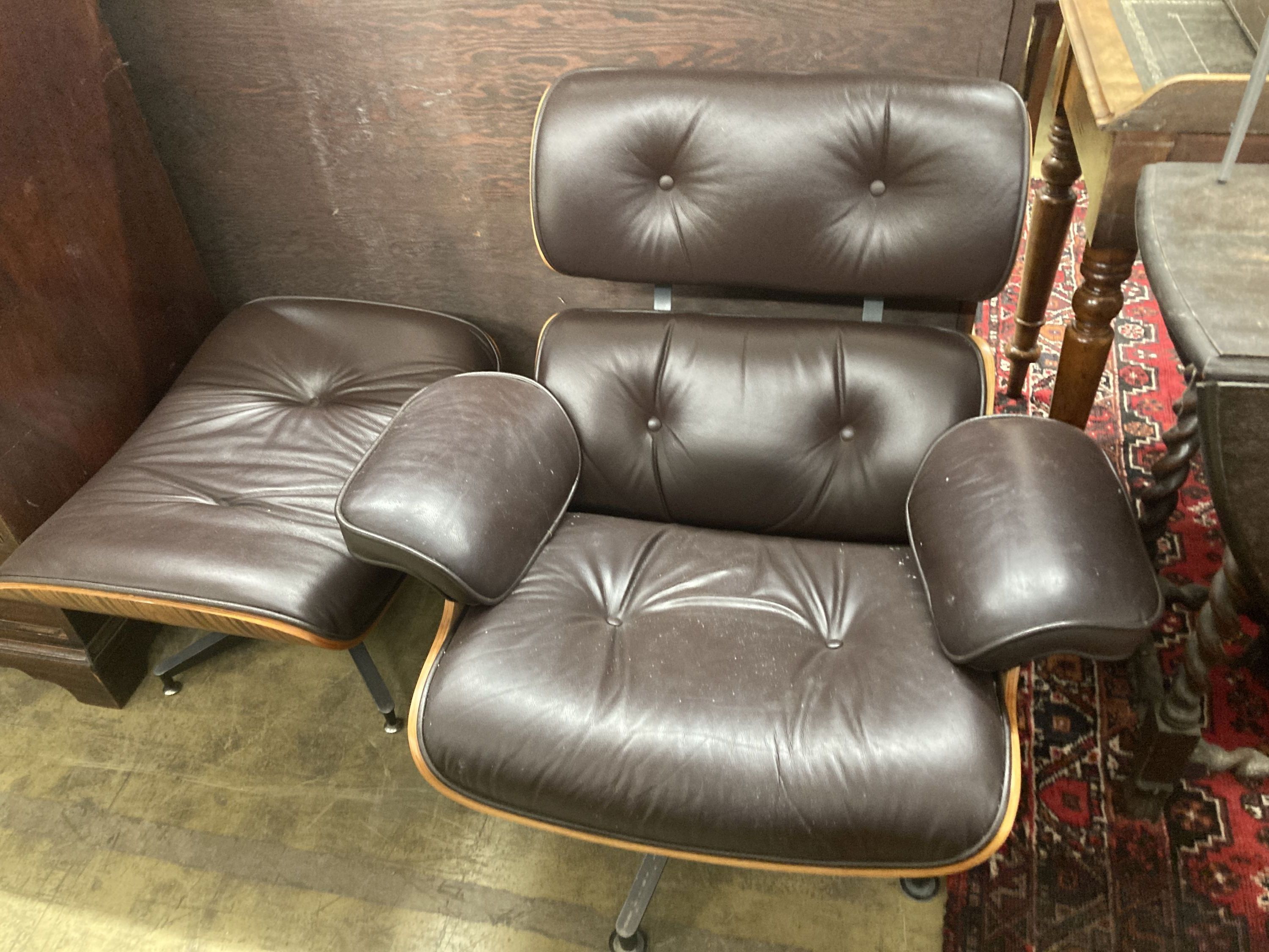 An Eames style modern buttoned dark brown leather swivel chair, width 92cm, depth 74cm, height 78cm and matching stool